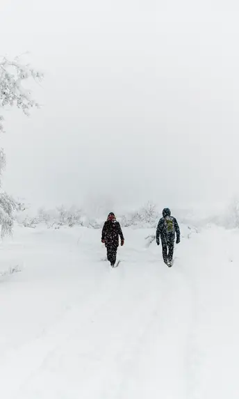 glockna, dein Hotel für Wanderurlaub bei den Hohen Tauern Zwei Personen wandern durch verschneite Winterlandschaft bei Nebel