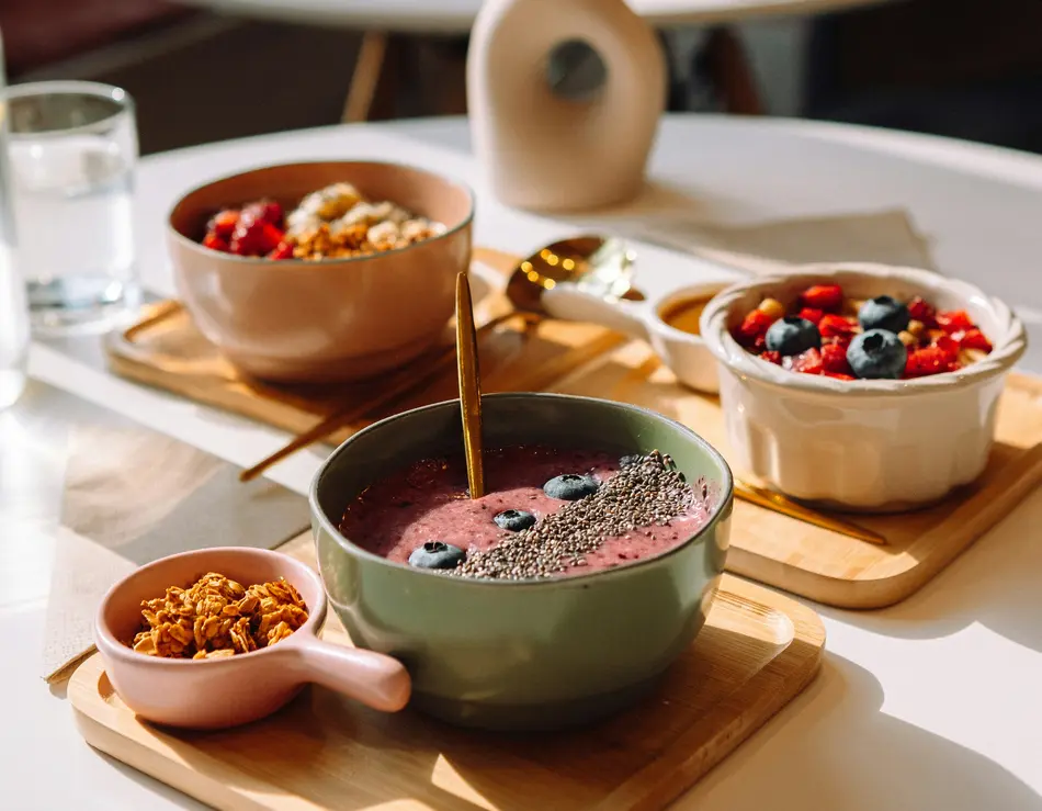 glockna, dein Genusshotel im SalzburgerLand Gesunde Frühstücksschalen mit Beeren, Chiasamen und Müsli auf Holzbrettern