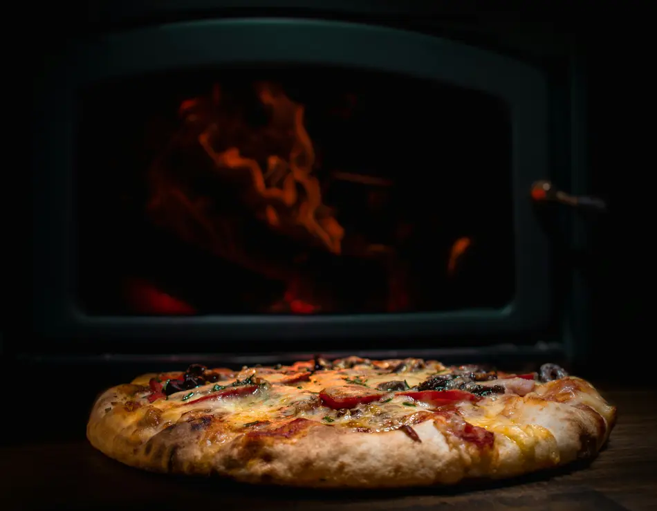 Restaurant in Fusch an der Großglocknerstraße gesucht? Frisch gebackene Pizza vor einem Holzofen mit Flammen