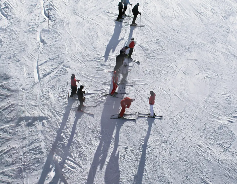 Skiurlaub in Fusch mit Blick auf den Großglockner Gruppe von Skifahrern auf schneebedeckter Piste mit langen Schatten