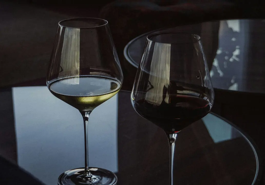 Inclusive services at Designer Motel glockna Two wine glasses with red and white wine on a glass table in a dimly lit room