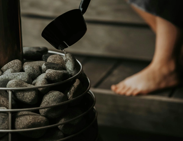 glockna, your wellness hotel in the Salzburg region Water being poured with a ladle on hot stones in a sauna