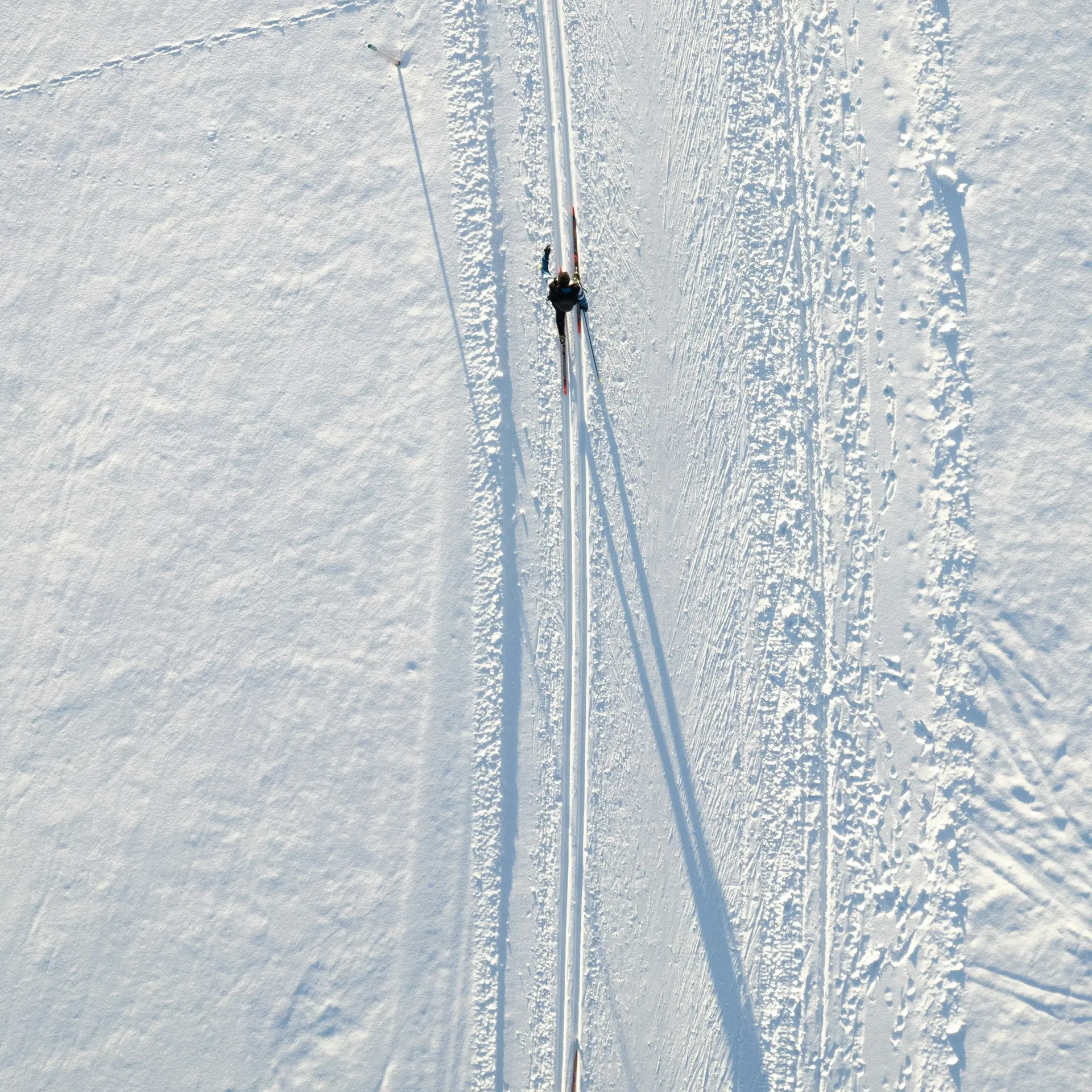 Zwei Langläufer auf einer gespurten Loipe im Schnee von oben gesehen