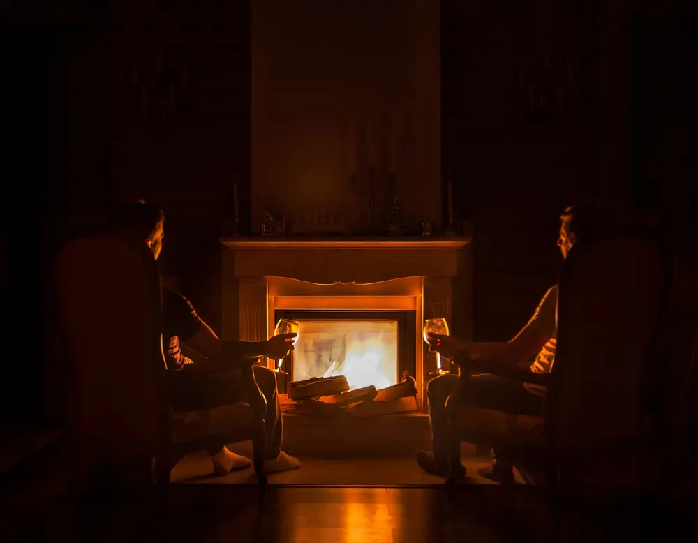 Events on the Grossglockner High Alpine Road Two people sitting with wine glasses in front of a fireplace in a dark room