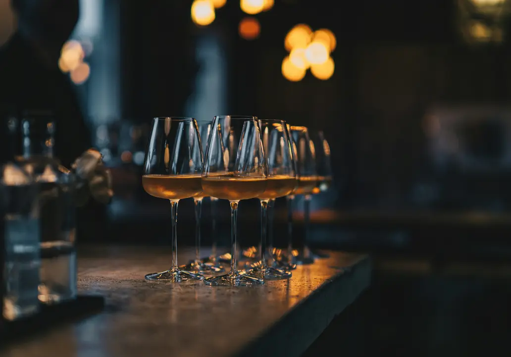 Events on the Grossglockner High Alpine Road Several wine glasses with white wine on a bar counter in dim lighting