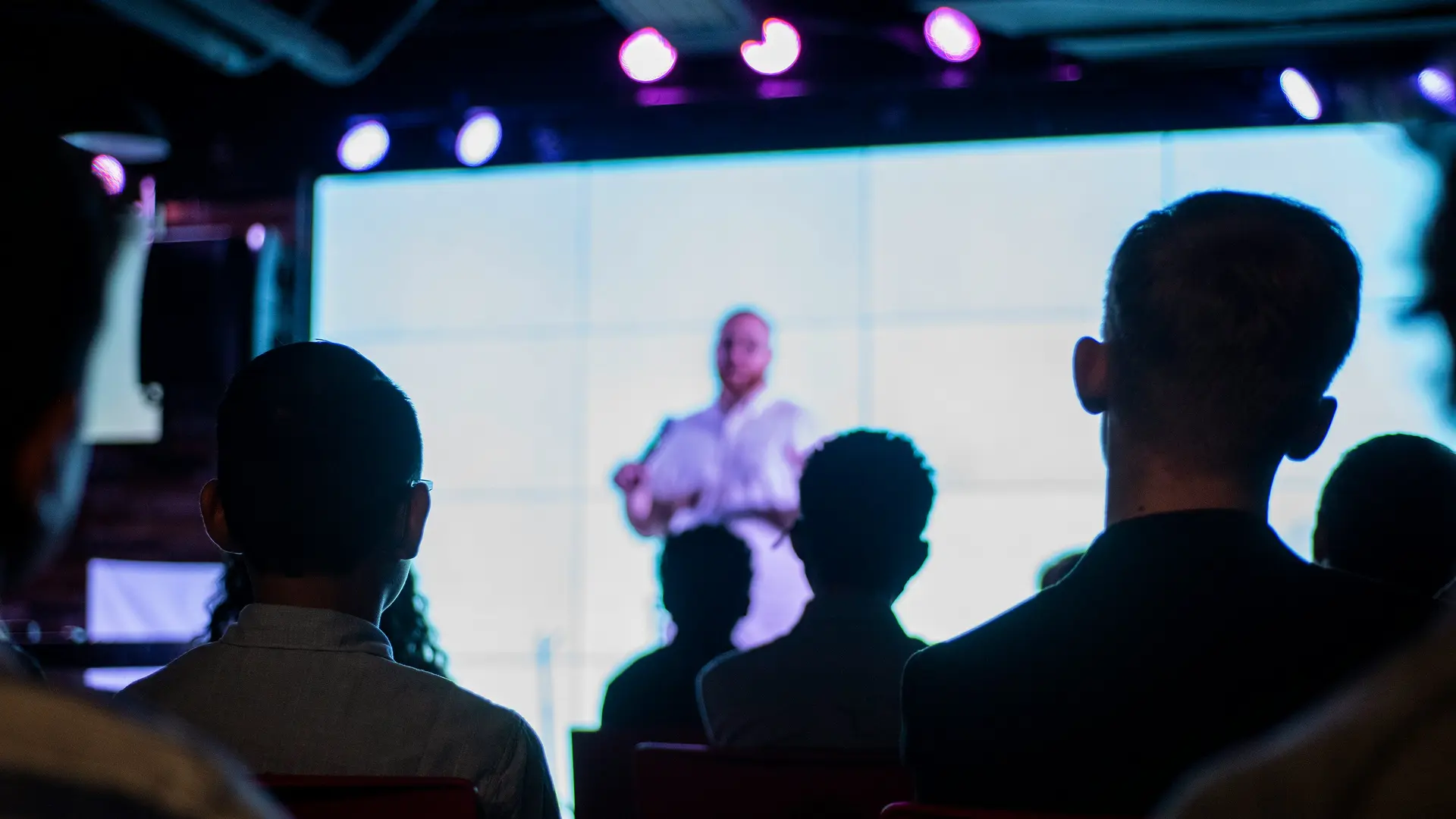 The business hotel in the Salzburg region Audience listening to a speaker on stage with bright screen in the background