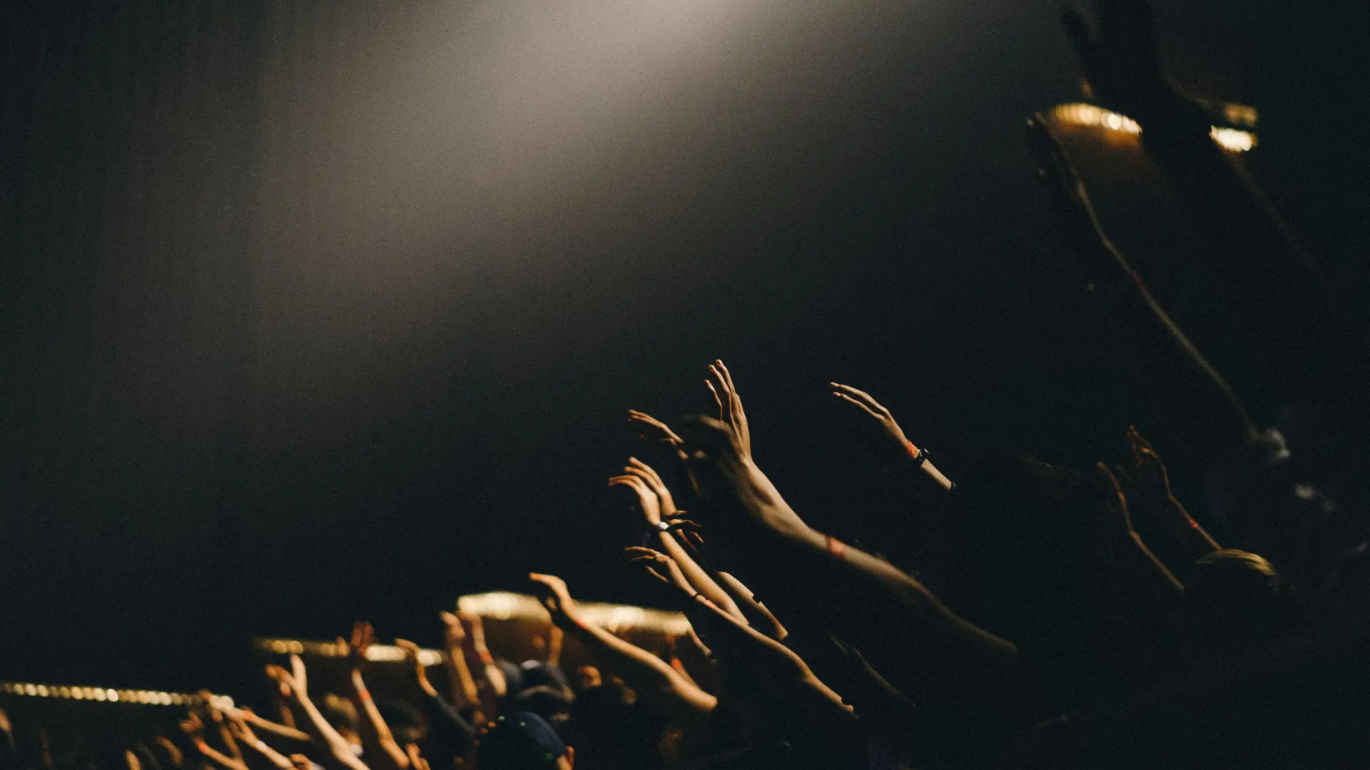 Events im SalzburgerLand Menschen heben bei Konzert ihre Hände in die Luft vor dunklem Hintergrund