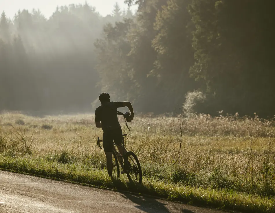 Dein Bike-Hotel im SalzburgerLand: glockna Radfahrer mit Fahrrad am Straßenrand bei nebligem Morgenlicht im Wald