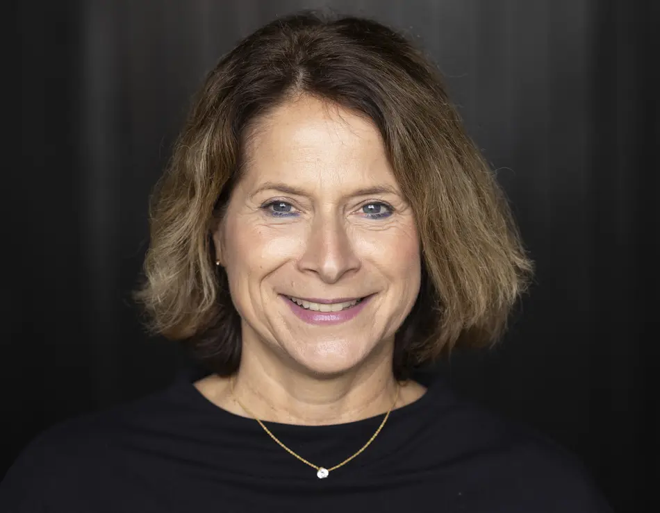 glockna in the press Woman with short brown hair wearing black top smiling against dark background
