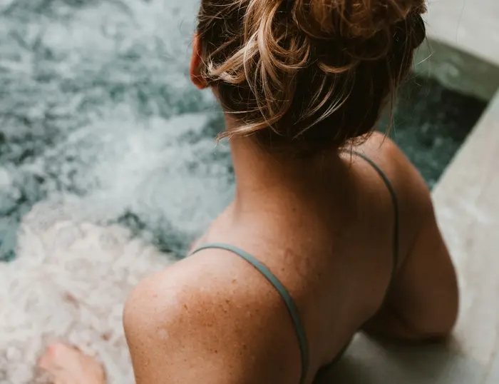 Der Aktivurlaub im SalzburgerLand mit Beschleuniger Frau mit Dutt entspannt im Whirlpool mit sprudelndem Wasser