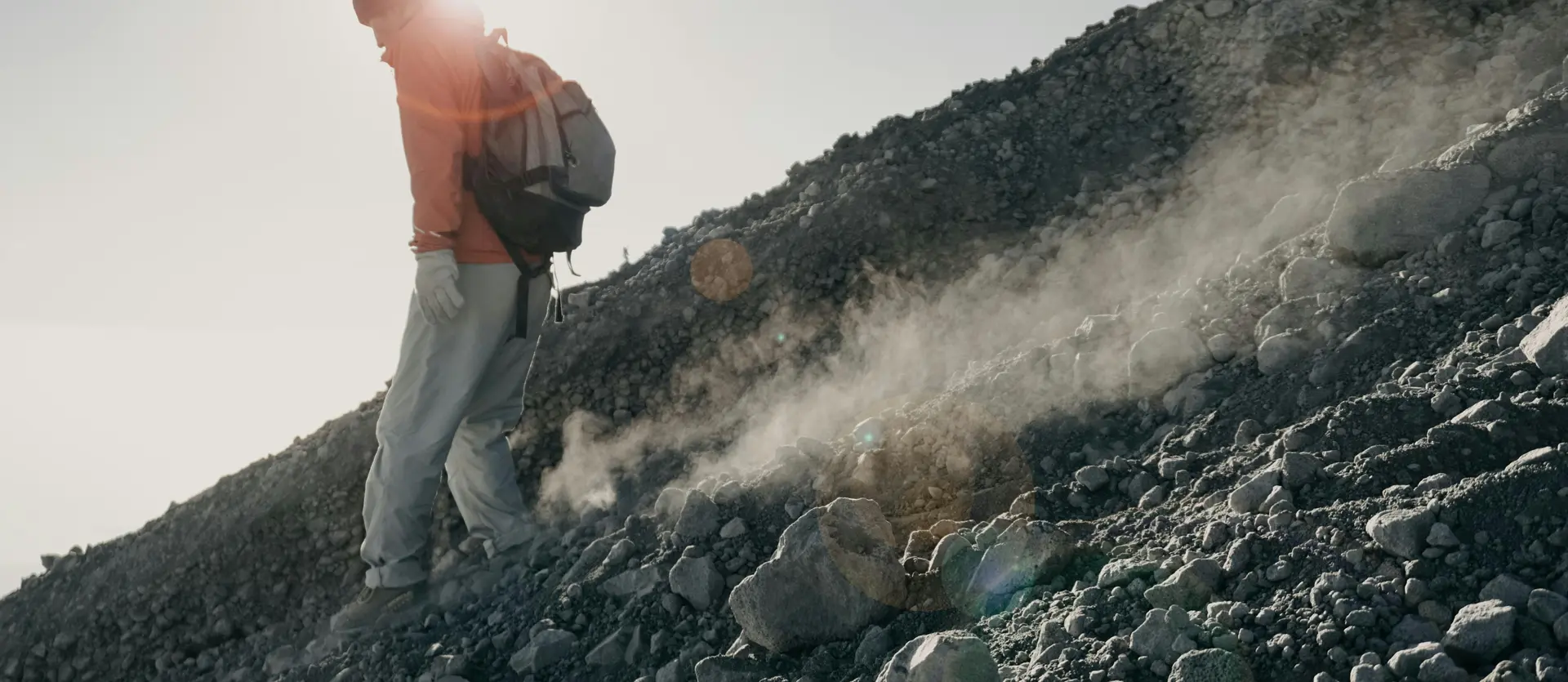 Bergsteigen mit Blick auf den Großglockner Wanderer mit Rucksack auf steinigem Vulkanhang bei Sonnenlicht