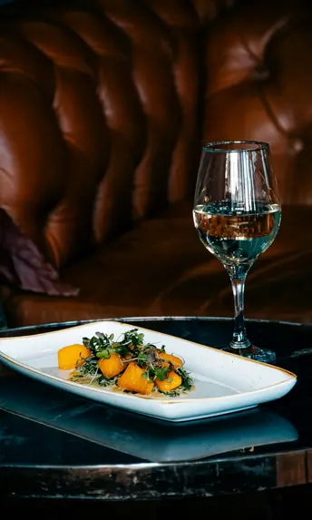Inclusive services at Designer Motel glockna Glass of white wine and plate with pumpkin and microgreens on black table