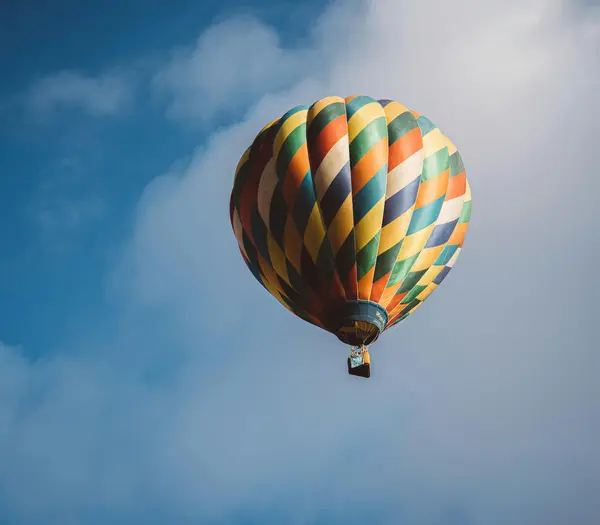 Bunter Heißluftballon vor blauem Himmel mit Wolken