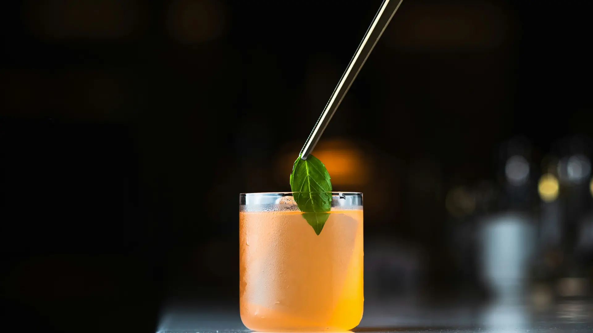 glockna bar – drinks & sundowners on the Grossglockner Road Hand placing a green leaf garnish on an orange cocktail with tongs