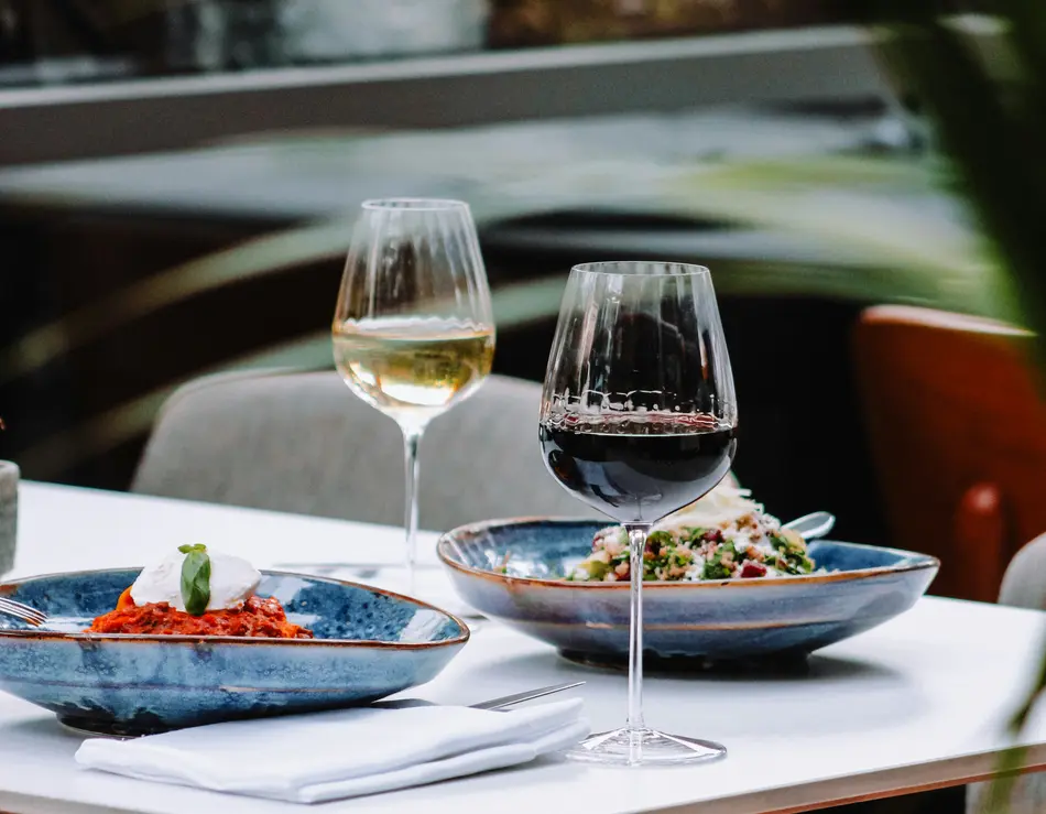 Beste Kulinarik im Hotel in Österreich: direkt in Fusch Tisch mit zwei Tellern Pasta und je einem Glas Rot- und Weißwein im Restaurant