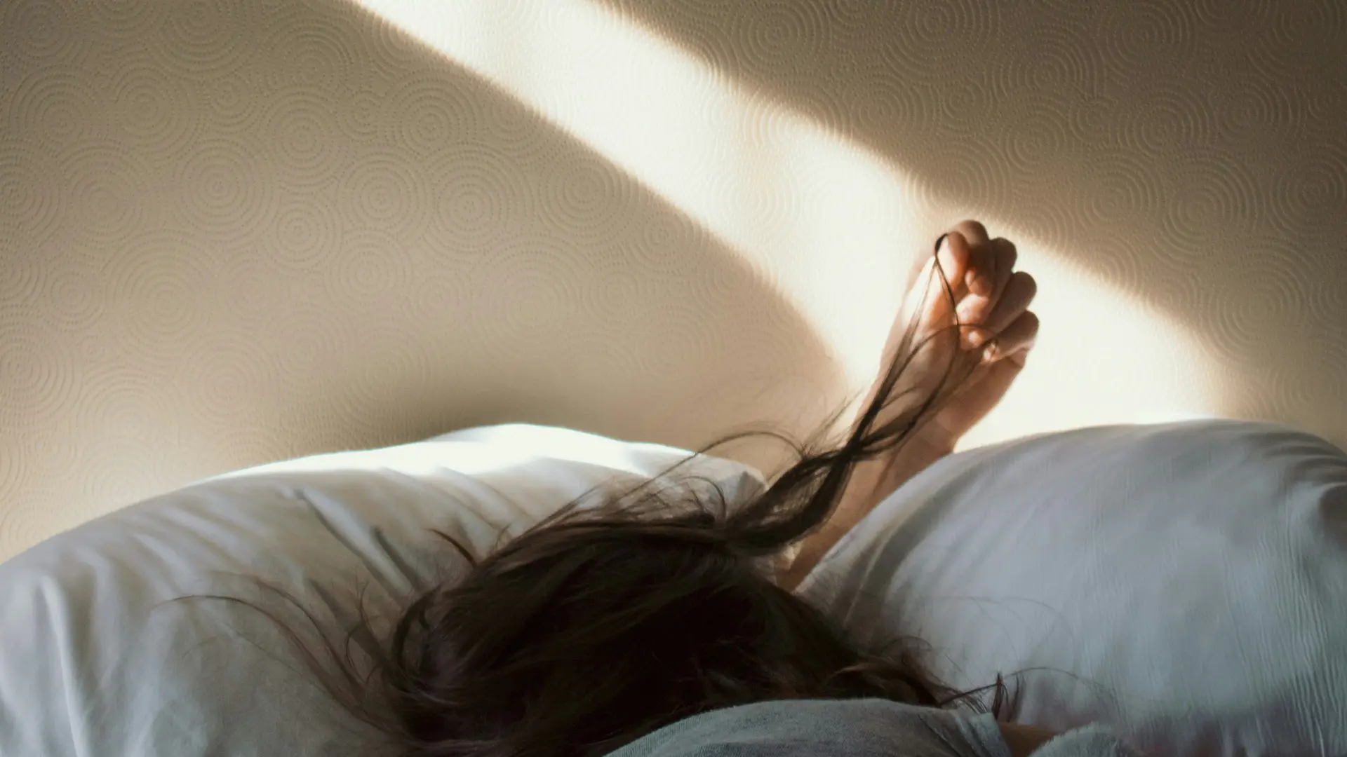 Übernachtung an der Großglockner Hochalpenstraße Person liegt schlafend im Bett mit Sonnenlicht auf der Wand