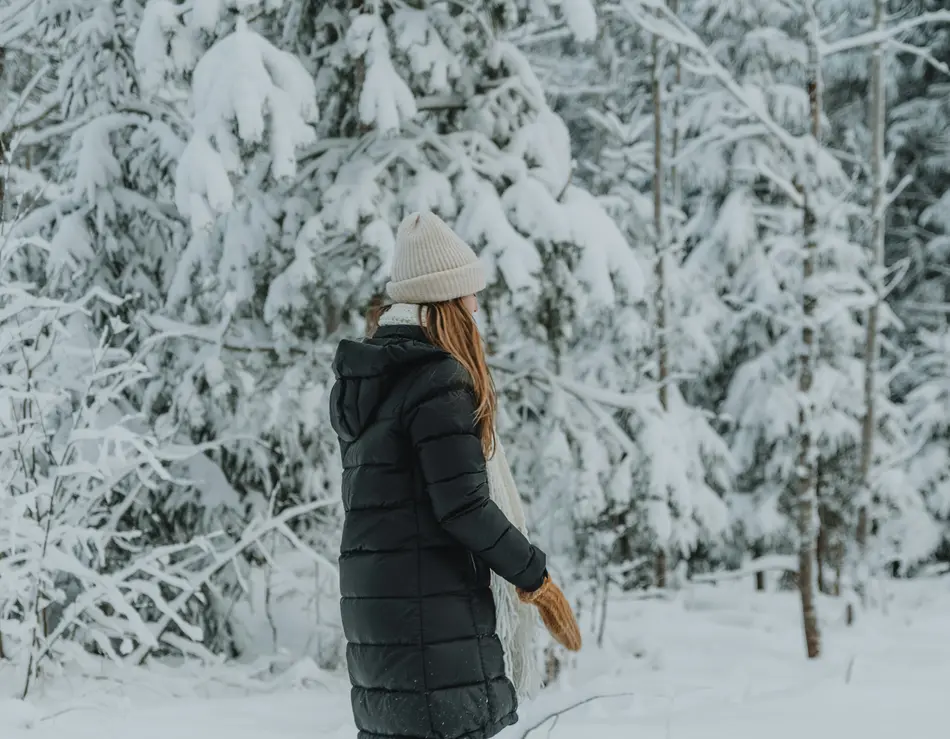 glockna, dein Hotel für Wanderurlaub bei den Hohen Tauern Frau in Winterkleidung steht vor verschneiten Tannenbäumen im Wald