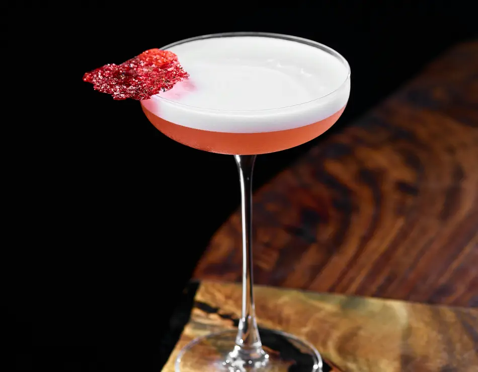 glockna, dein Genusshotel im SalzburgerLand Cocktail mit Schaum und roter Dekoration in einem Cocktailglas auf Holztisch