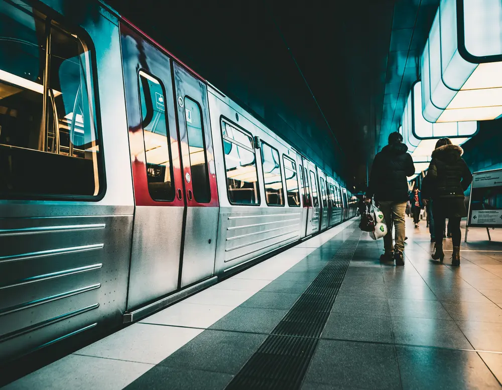Directions to the Grossglockner High Alpine Road and glockna Subway train at a lit station with passengers walking on the platform