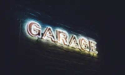 Events im SalzburgerLand Leuchtreklame mit dem Wort Garage an einer dunklen Backsteinwand
