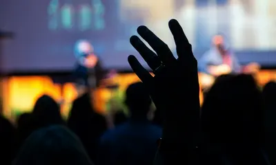 Events im SalzburgerLand Schatten einer erhobenen Hand vor einer Bühne mit unscharfen Musikern und Publikum