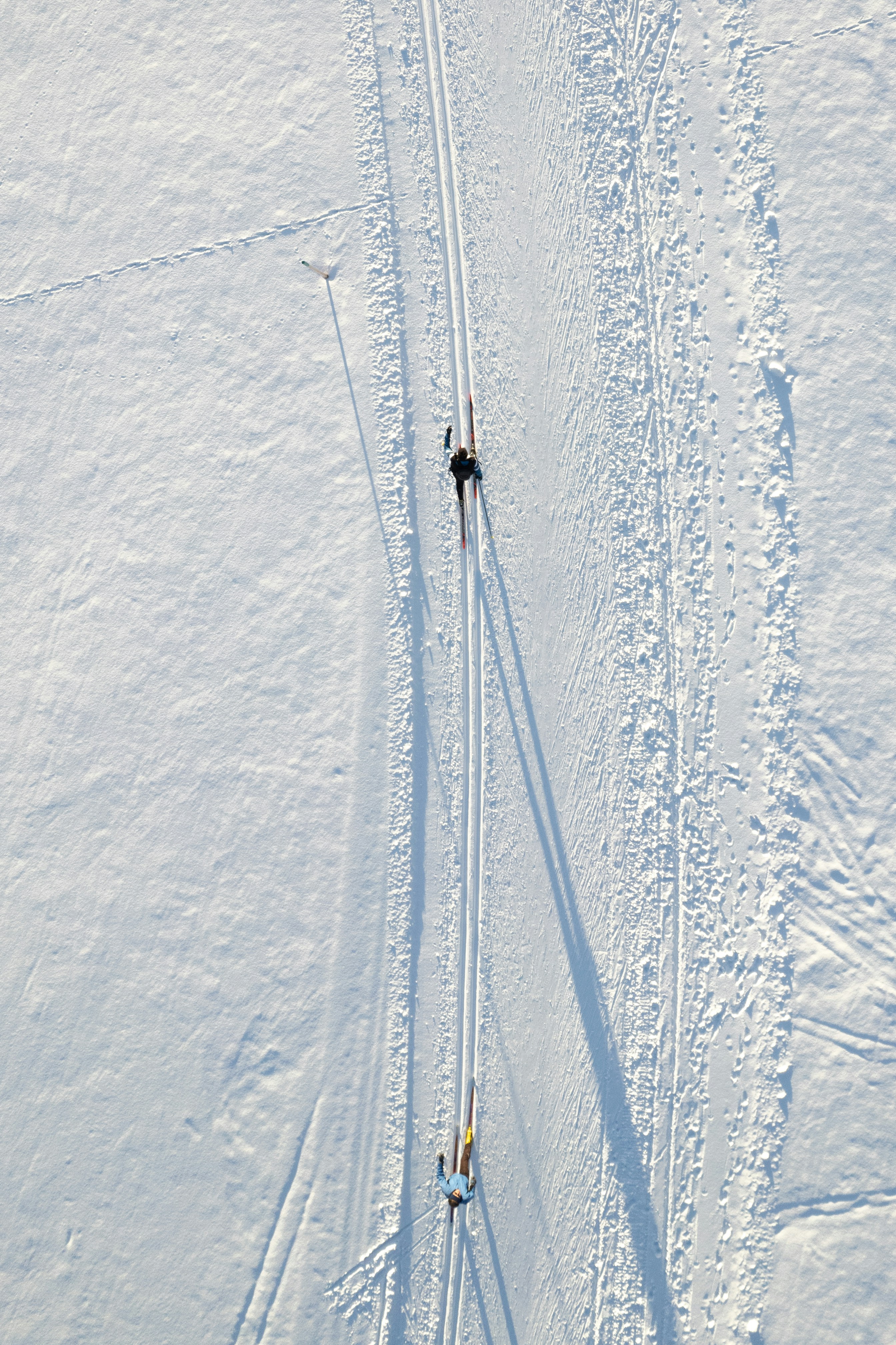 Zwei Langläufer auf einer gespurten Loipe im Schnee von oben gesehen