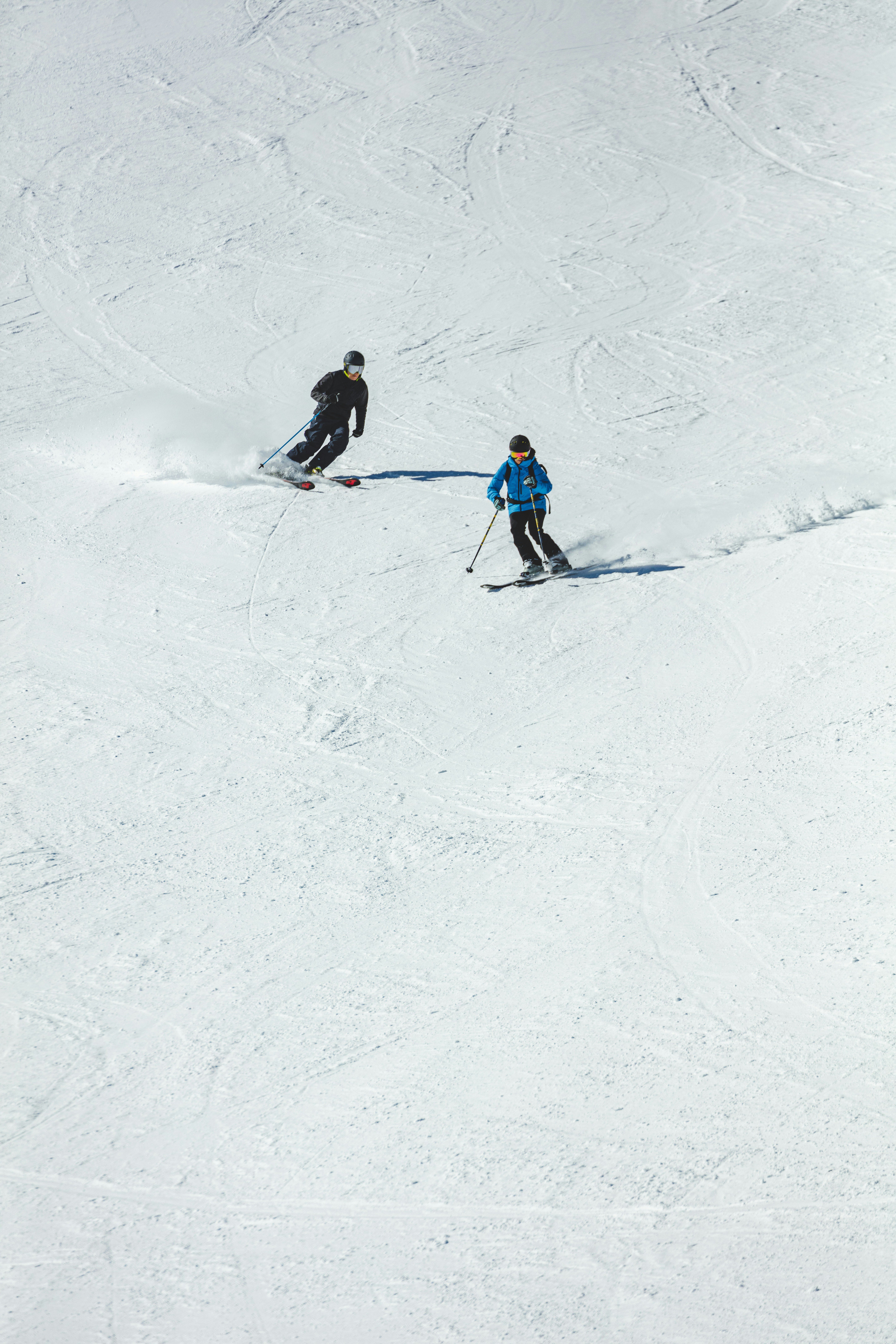 Zwei Skifahrer fahren nebeneinander auf einer verschneiten Piste