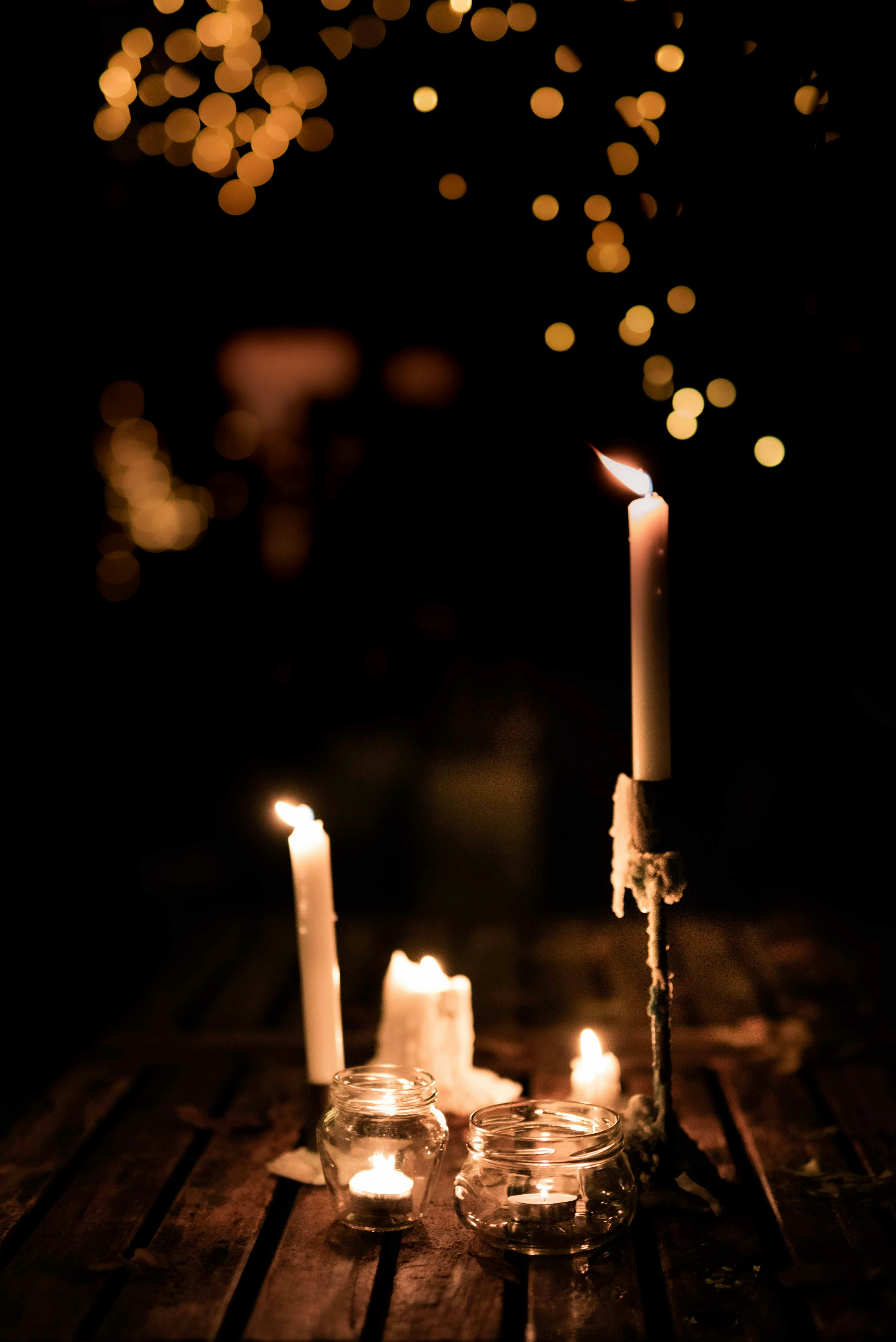 Events on the Grossglockner High Alpine Road Several lit candles on a wooden table at night with bokeh lights in the background